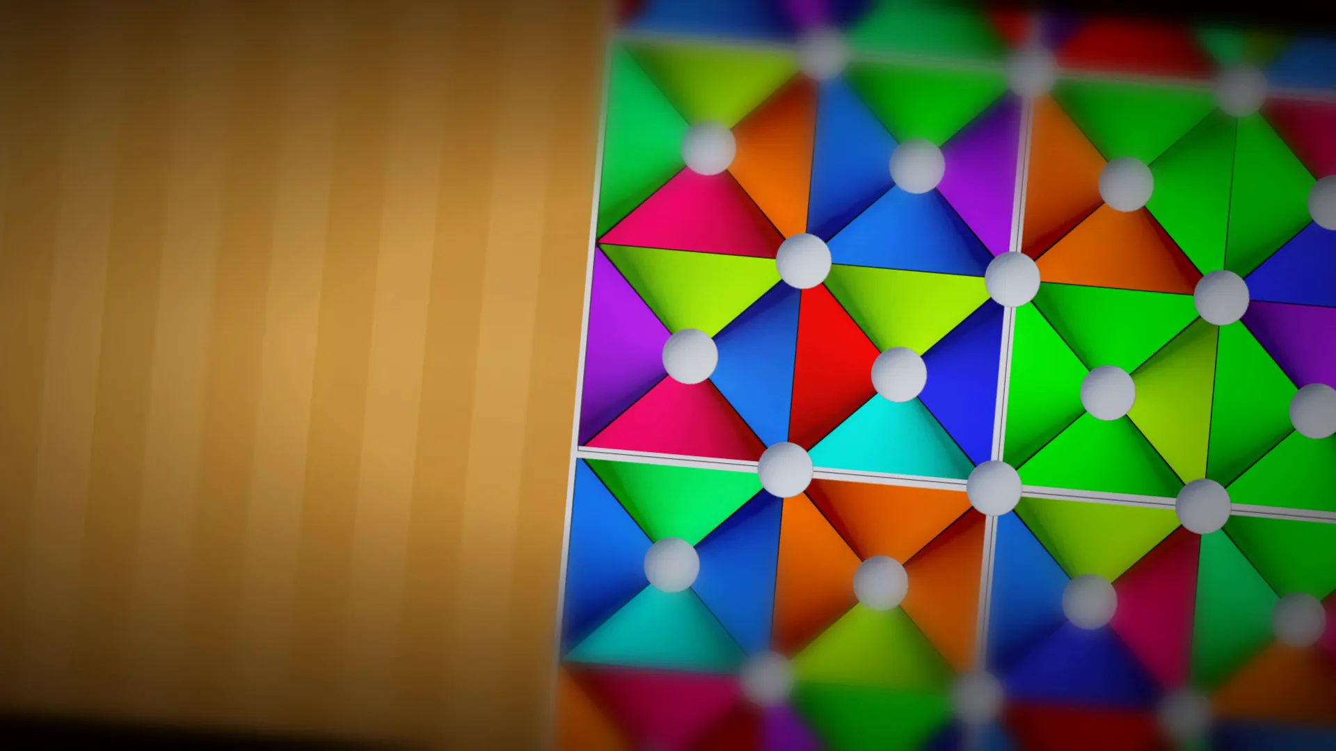 Close-up of a Trigonix board: colored triangles meet at white dots, on a wooden table.